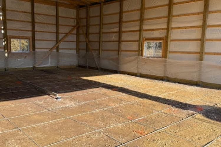 Interior view of a newly constructed building with framed walls and concrete floor preparation.