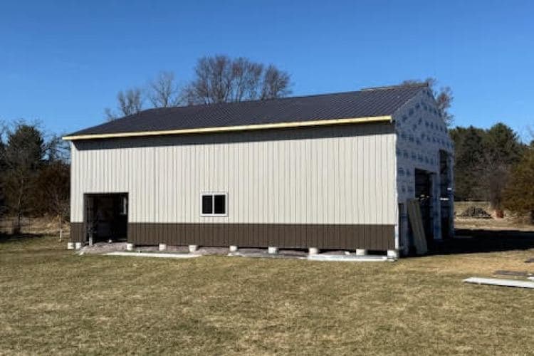 Newly constructed metal barn with a sloped roof and a modern design on green grass.