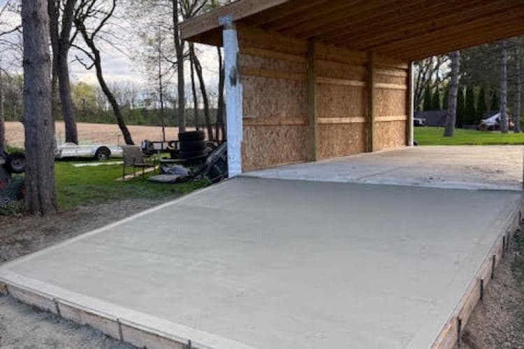 Concrete slab construction for a building with surrounding trees and open field.