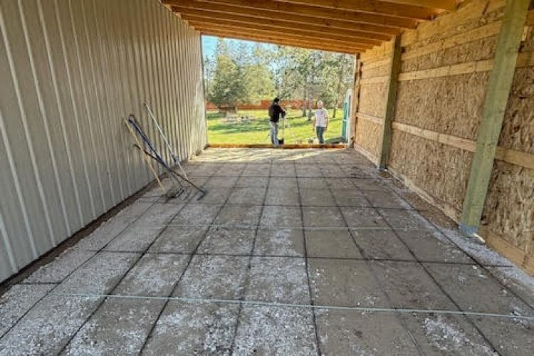 Interior of a building under construction, featuring a concrete floor and two workers.