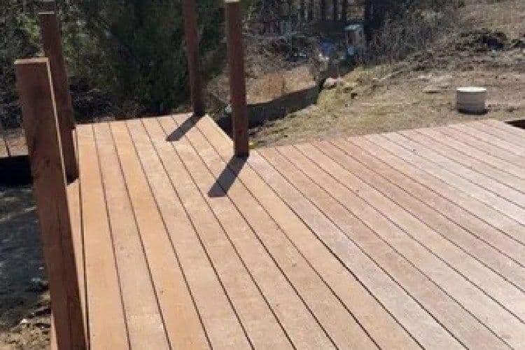 Wooden deck construction with railing set in a natural outdoor landscape.