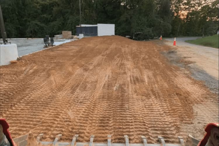 Site preparation with freshly graded dirt and tire tracks for construction project.
