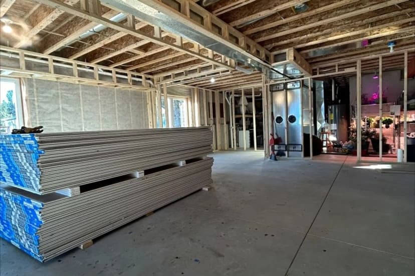 Interior of a construction site with stacked drywall and framed walls, showcasing ongoing renovation.