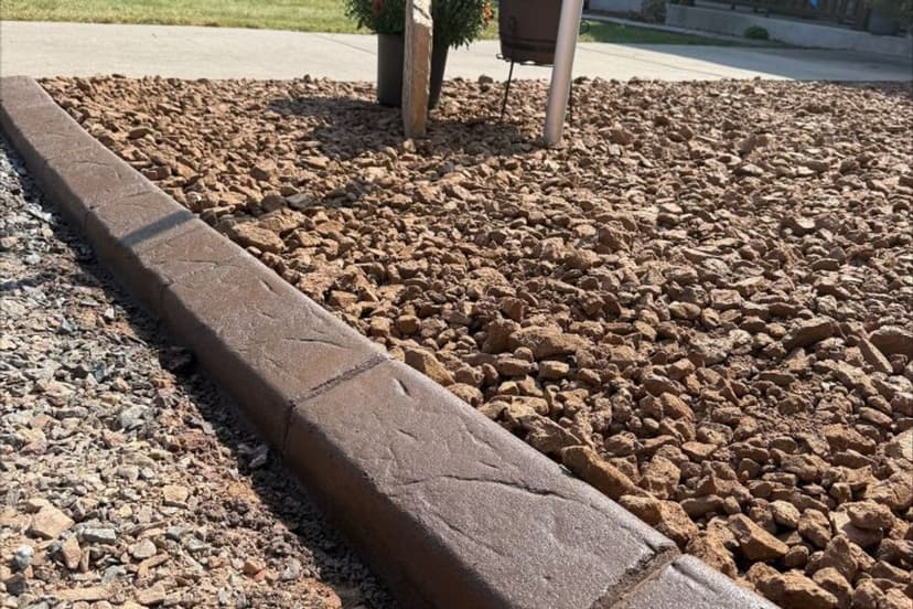 Decorative concrete border with gravel landscaping in a residential yard.