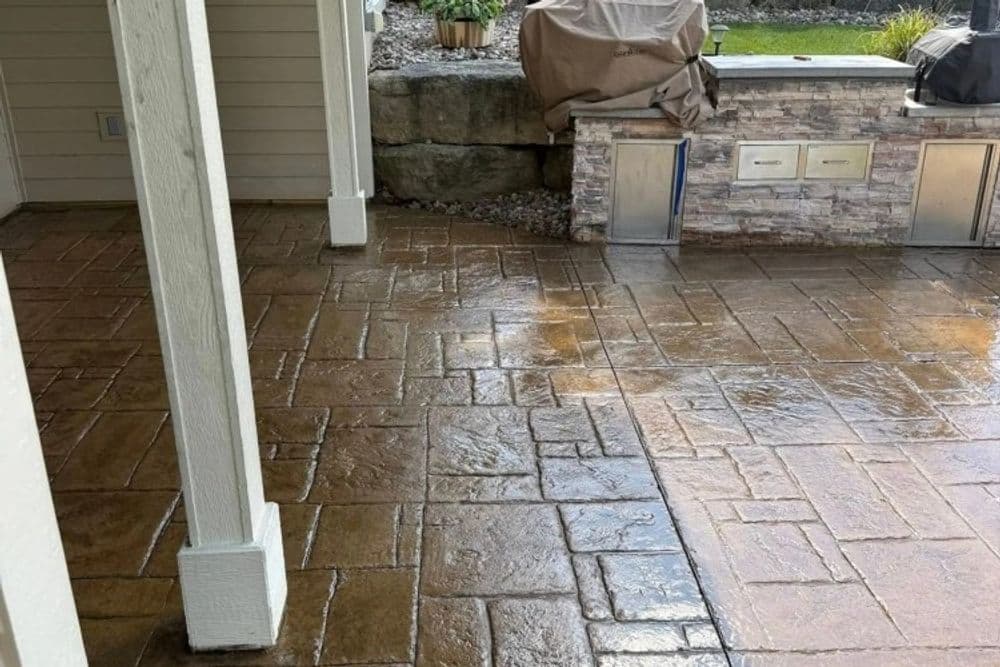 Stylish stamped concrete patio with a stone wall and outdoor seating area.