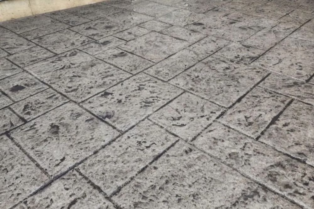 Textured concrete patio with a stamped stone pattern and gray surface.
